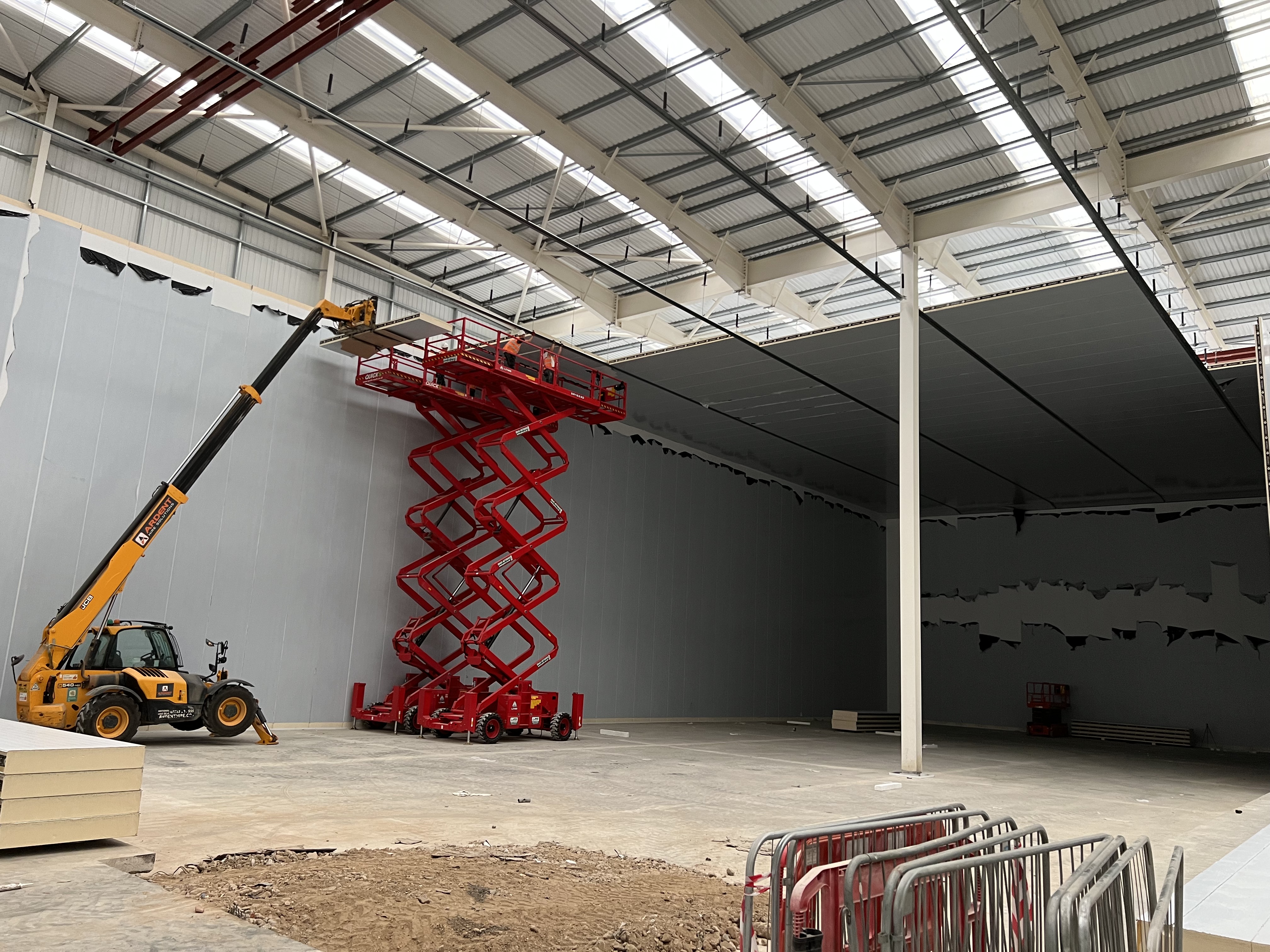 Large-scale insulated panel installation with telehandler and scissor lift